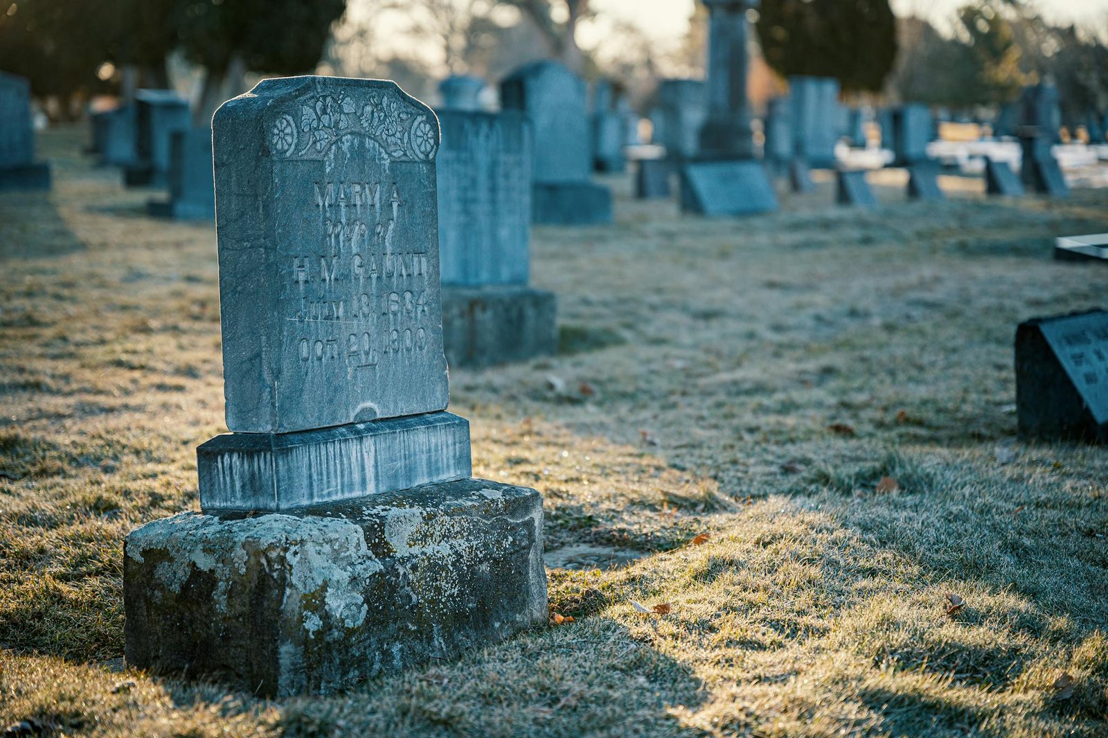 A peaceful cemetery scene featuring an old tombstone on a frosty morning.