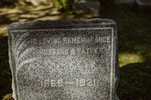 Close-up of a granite tombstone engraved with 'In Loving Remembrance' and dates from 1869-1921.