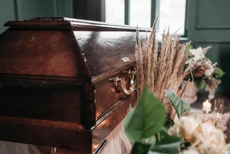 A beautiful funeral display featuring a wooden coffin with flowers and candles indoors. How to plan a funeral.