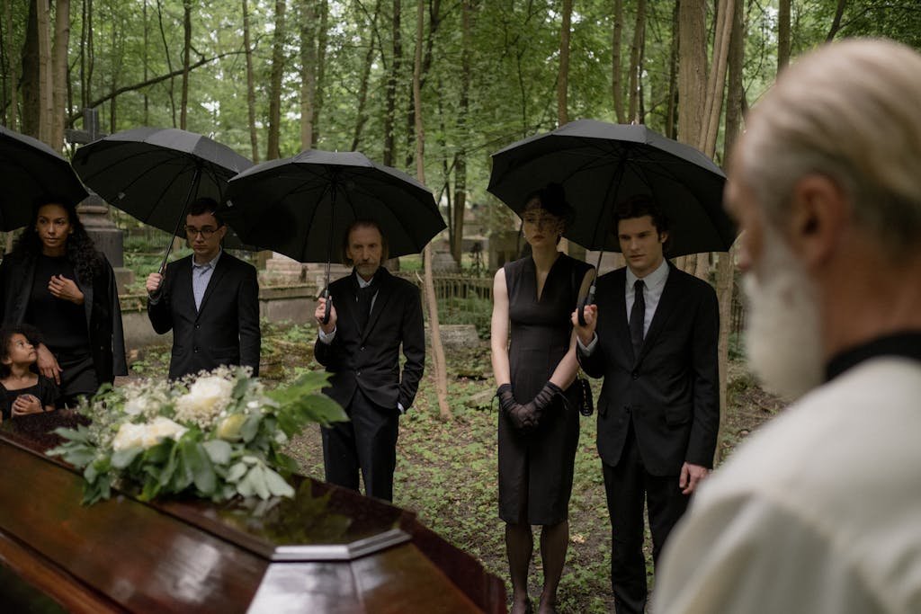 A group mourns during a funeral gathering in a forest cemetery.