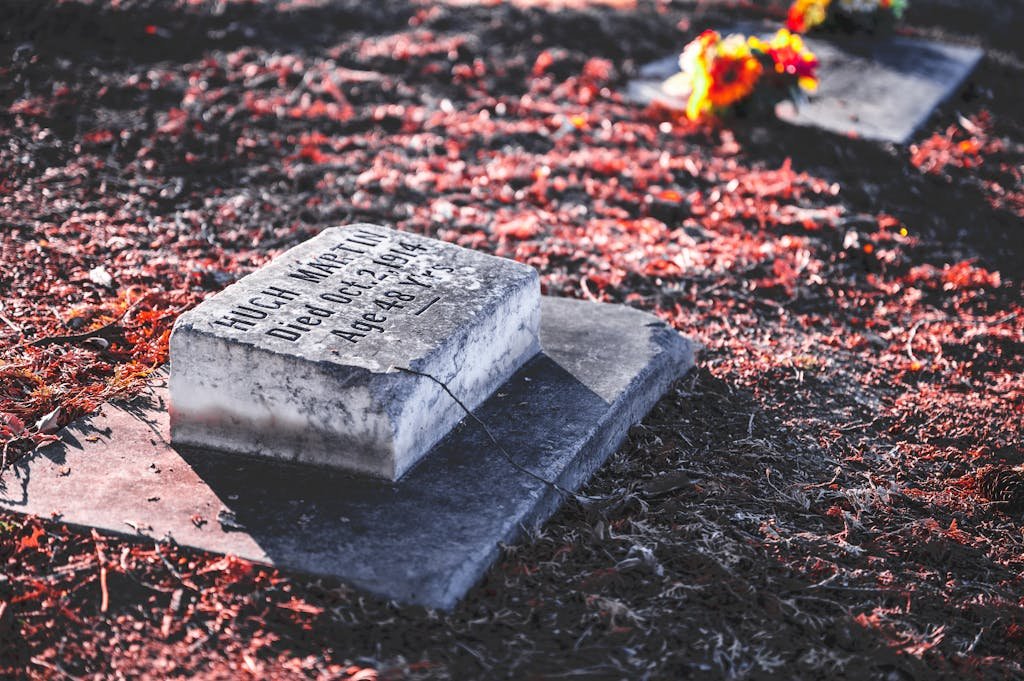 A peaceful autumn cemetery scene with a weathered tombstone and vibrant leaves. How much does it cost to be buried.