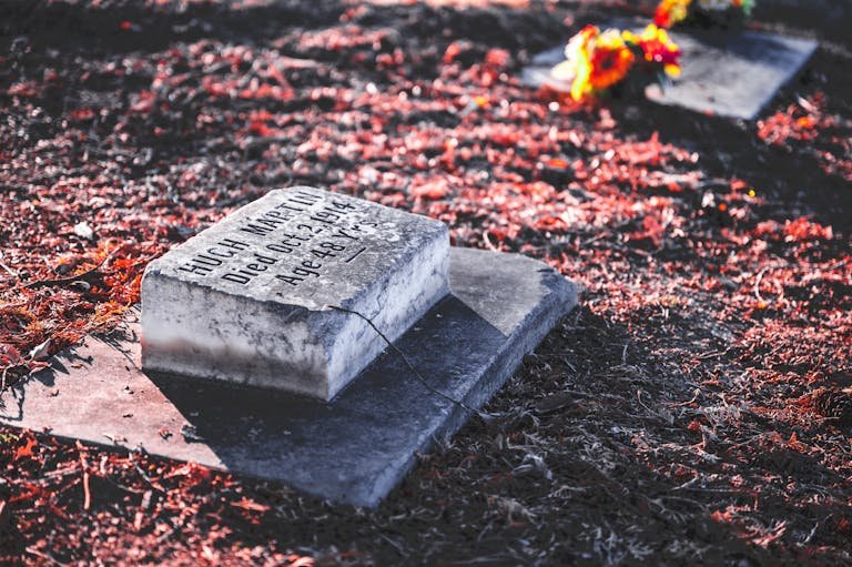 A peaceful autumn cemetery scene with a weathered tombstone and vibrant leaves. How much does it cost to be buried.