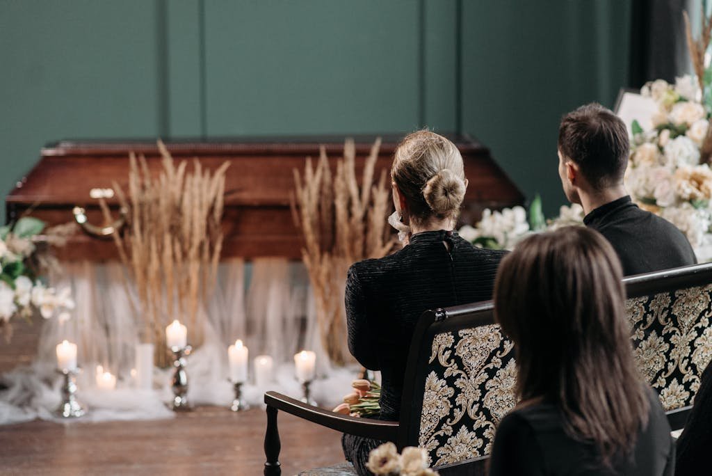 A respectful gathering of family and friends at a funeral service indoors, with floral arrangements and candles. What to say at a funeral.