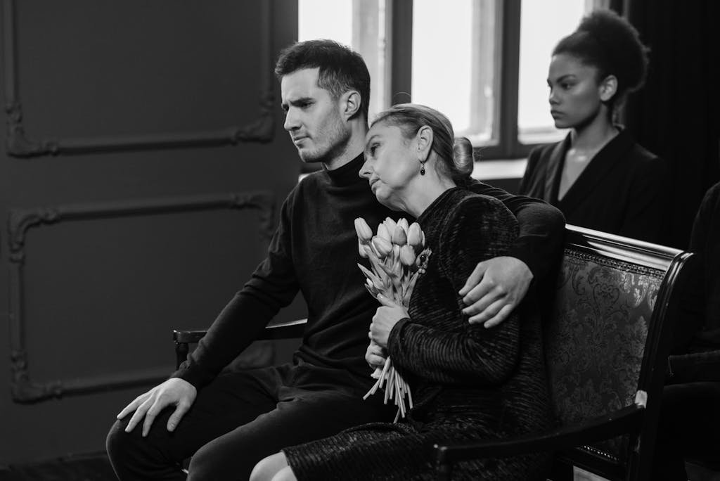 A somber black and white image capturing a grieving family at a funeral. What to wear to a funeral.