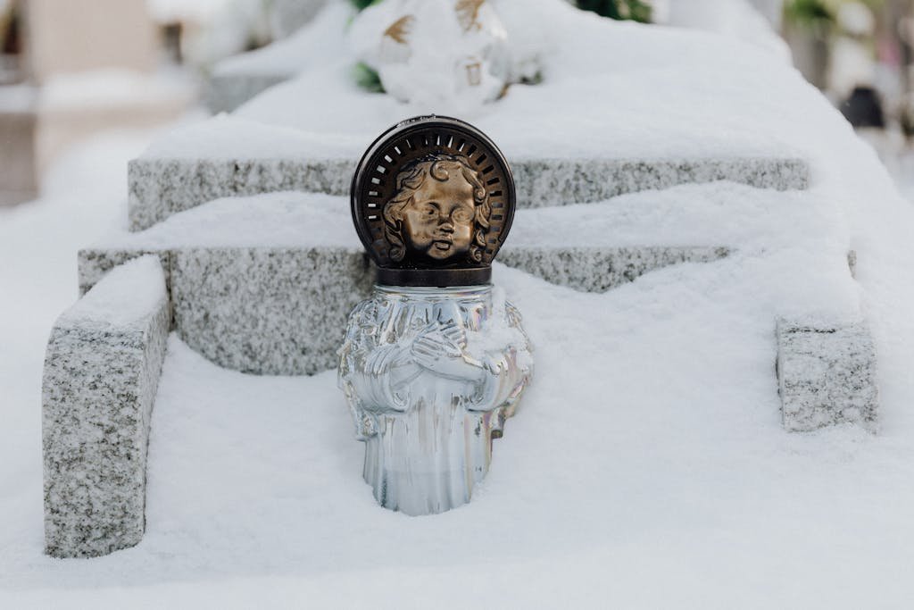 Close-up of an angel statue partially covered in snow, creating a serene winter scene.