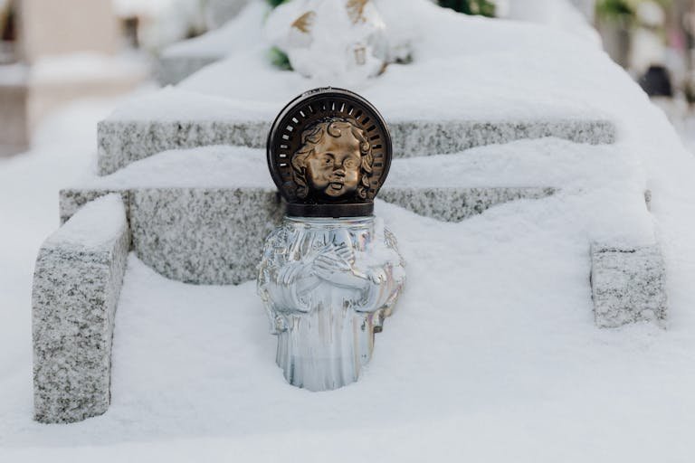 Close-up of an angel statue partially covered in snow, creating a serene winter scene.