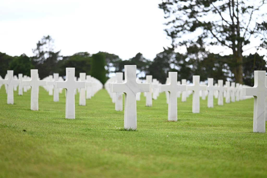 Rows of white crosses in a tranquil military cemetery symbolizing sacrifice and remembrance.